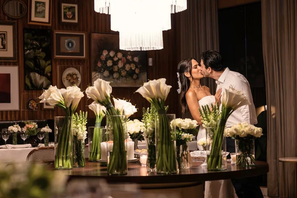 Noivos em mesa de doces com callas